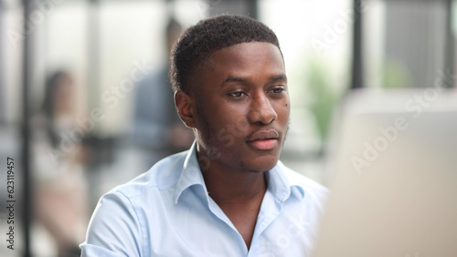 Thoughtful black man in eyeglasses stack with hard task, looking at computer screen, thinking of problem solution