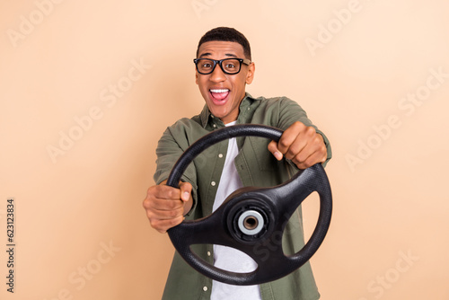 Photo of funky astonished person hands hold wheel steering open mouth good mood isolated on beige color background