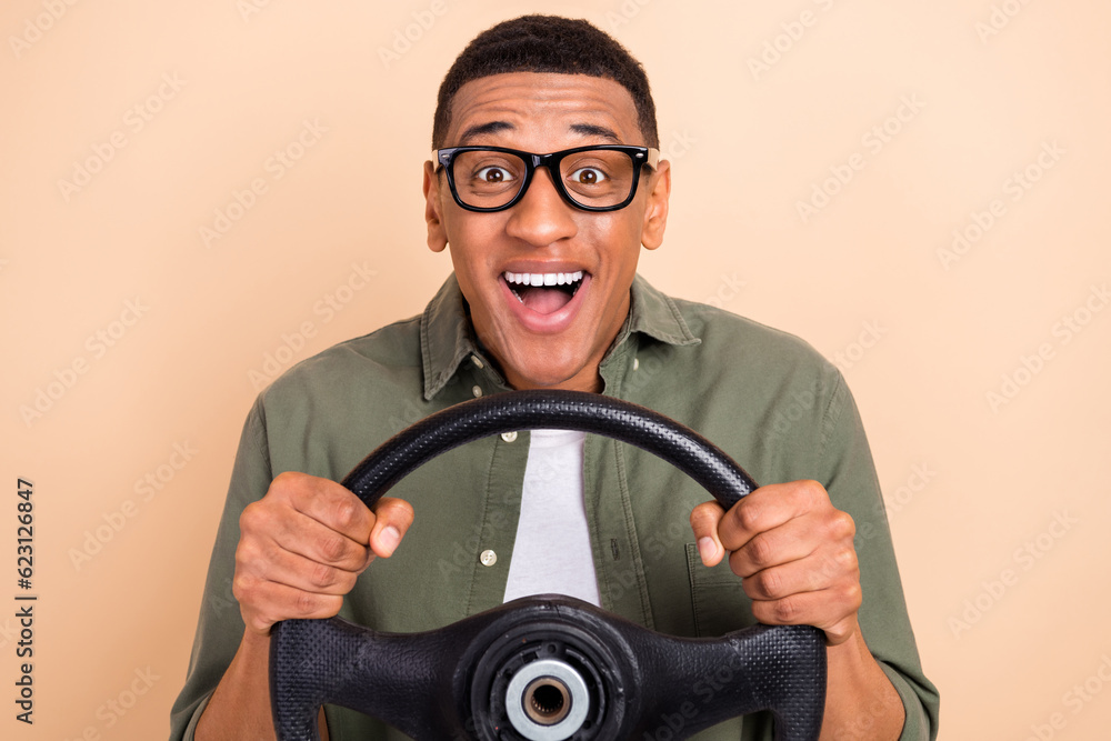 Photo of excited funky guy dressed khaki shirt eyewear driving automobile isolated beige color background Photo of excited funky guy dressed khaki shirt eyewear driving automobile isolated beige color background