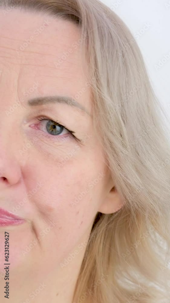 Photo of thoughtful woman bites lower lip, looks with dreamy expression aside, wearing stylish beige hoodie, stands against white wall. Copy space for your text. High quality photo Photo of thoughtful woman bites lower lip, looks with dreamy expression aside, wearing stylish beige hoodie, stands against white wall. Copy space for your text. High quality photo