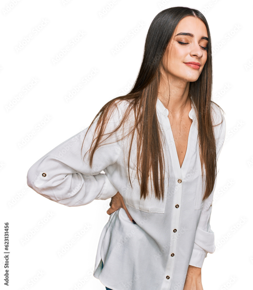 Young beautiful woman wearing casual white shirt suffering of backache, touching back with hand, muscular pain Young beautiful woman wearing casual white shirt suffering of backache, touching back with hand, muscular pain