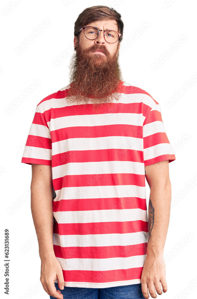 Handsome young red head man with long beard wearing casual clothes relaxed with serious expression on face. simple and natural looking at the camera. Handsome young red head man with long beard wearing casual clothes relaxed with serious expression on face. simple and natural looking at the camera.