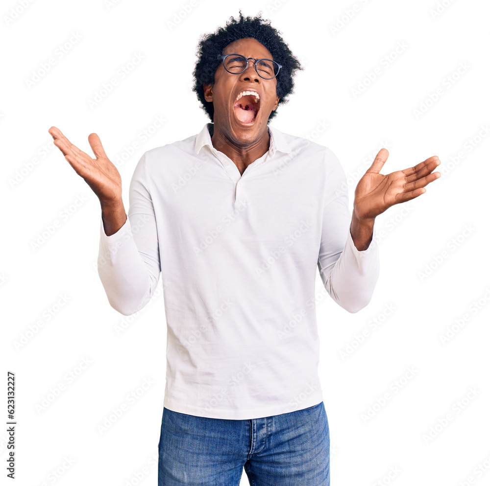 Handsome african american man with afro hair wearing casual clothes and glasses celebrating mad and crazy for success with arms raised and closed eyes screaming excited. winner concept Handsome african american man with afro hair wearing casual clothes and glasses celebrating mad and crazy for success with arms raised and closed eyes screaming excited. winner concept