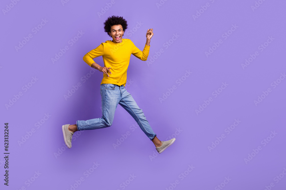Full length body photo of jumping crazy overjoyed optimistic funky wear denim jeans yellow shirt isolated on purple color background