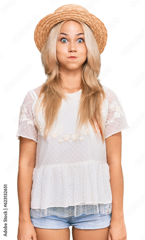 Young blonde girl wearing summer hat puffing cheeks with funny face. mouth inflated with air, crazy expression. Young blonde girl wearing summer hat puffing cheeks with funny face. mouth inflated with air, crazy expression.
