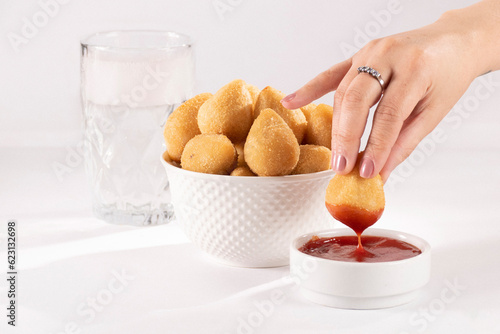 bowl of brazilian coxinhas and a female hand