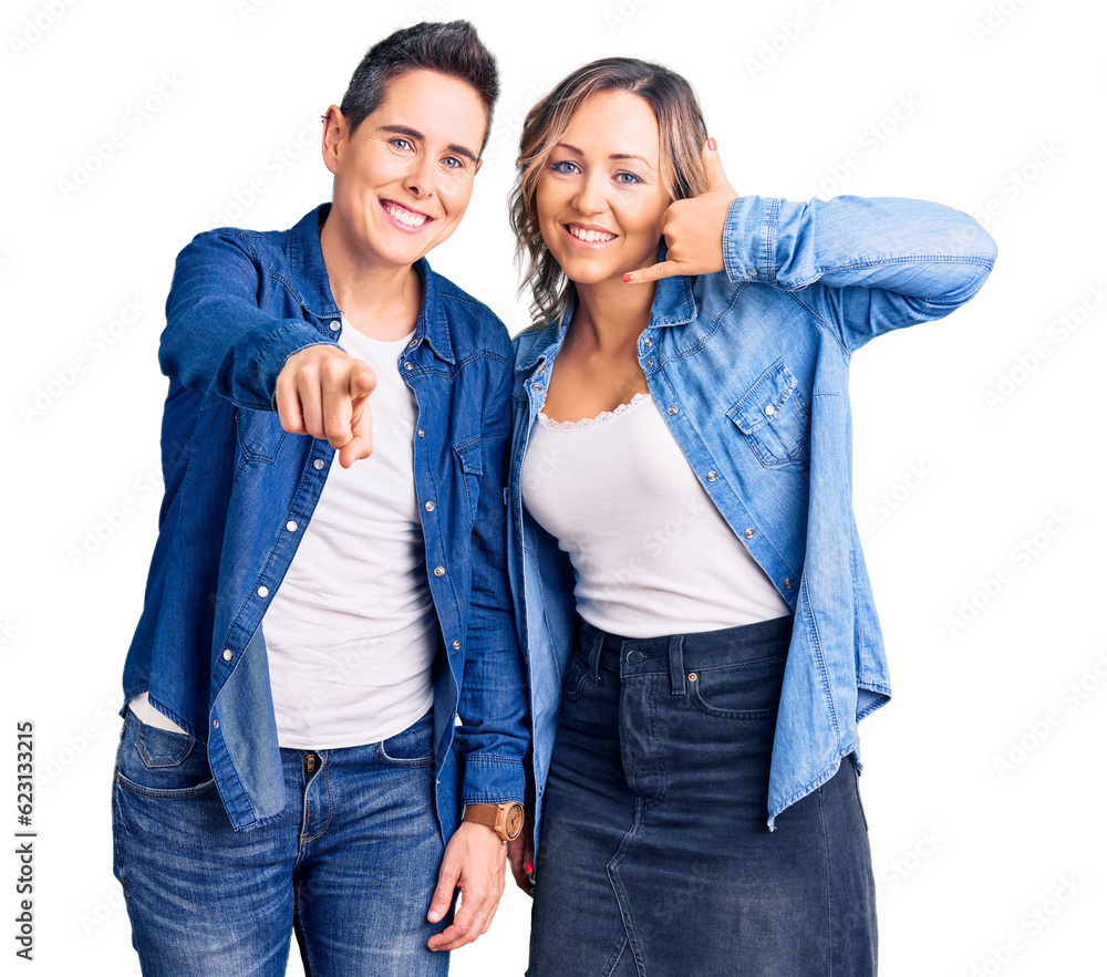 Couple of women wearing casual clothes smiling doing talking on the telephone gesture and pointing to you. call me. Couple of women wearing casual clothes smiling doing talking on the telephone gesture and pointing to you. call me.