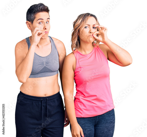 Couple of women wearing sportswear mouth and lips shut as zip with fingers. secret and silent, taboo talking