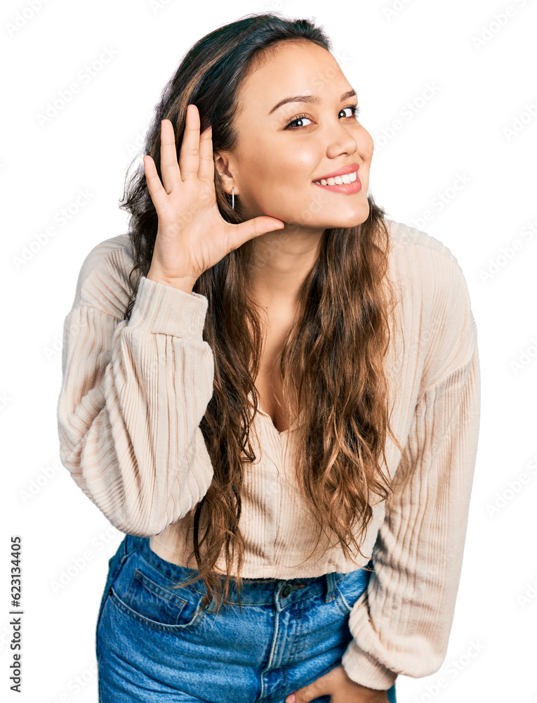 Young hispanic girl wearing casual clothes smiling with hand over ear listening and hearing to rumor or gossip. deafness concept.