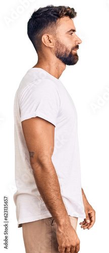 Plakat w ramie Young hispanic man wearing casual white tshirt looking to side, relax profile pose with natural face with confident smile.