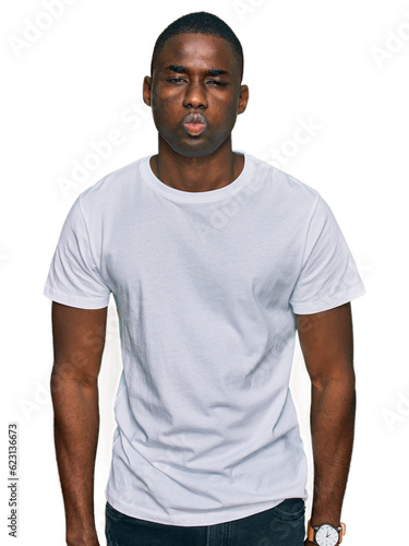 Young african american man wearing casual white t shirt making fish face with lips, crazy and comical gesture. funny expression.