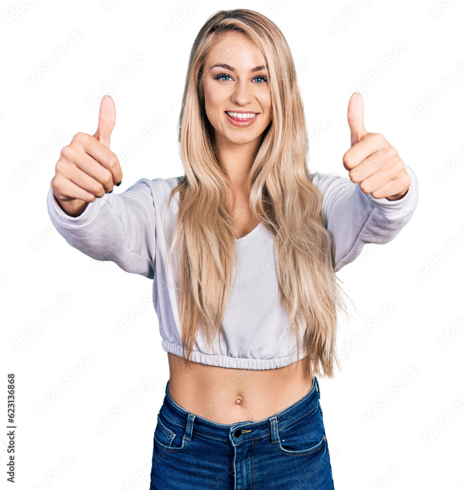 Beautiful young blonde woman wearing casual white sweater approving doing positive gesture with hand, thumbs up smiling and happy for success. winner gesture. Beautiful young blonde woman wearing casual white sweater approving doing positive gesture with hand, thumbs up smiling and happy for success. winner gesture.