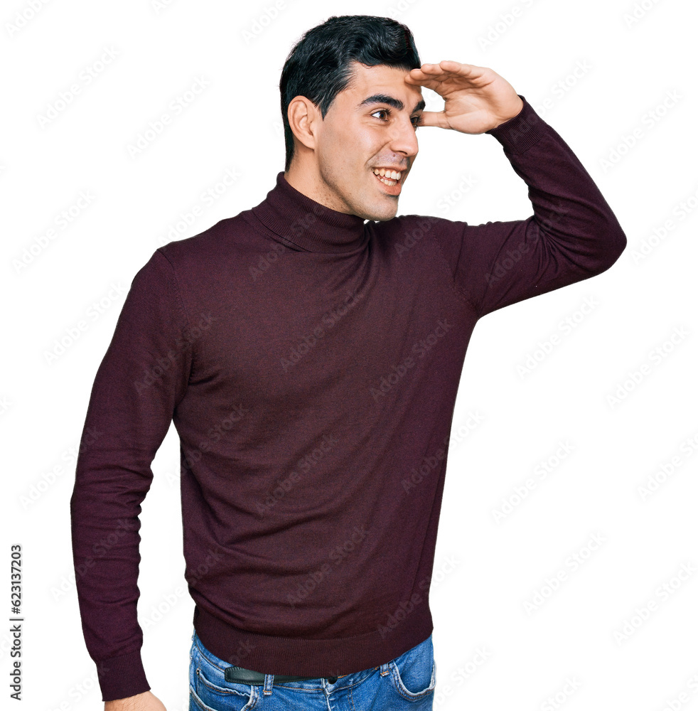 Handsome hispanic man wearing casual turtleneck sweater very happy and smiling looking far away with hand over head. searching concept. Handsome hispanic man wearing casual turtleneck sweater very happy and smiling looking far away with hand over head. searching concept.