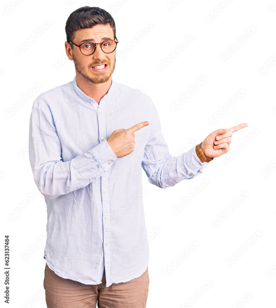 Handsome young man with bear wearing elegant business shirt and glasses pointing aside worried and nervous with both hands, concerned and surprised expression Handsome young man with bear wearing elegant business shirt and glasses pointing aside worried and nervous with both hands, concerned and surprised expression