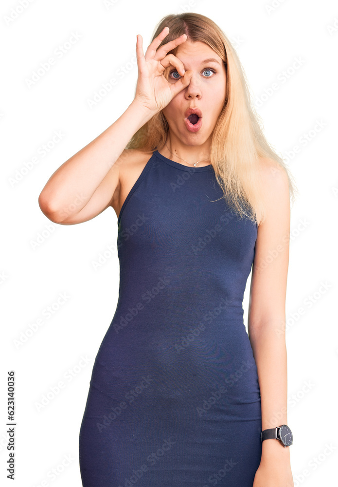 Young beautiful blonde woman wearing casual dress doing ok gesture shocked with surprised face, eye looking through fingers. unbelieving expression. Young beautiful blonde woman wearing casual dress doing ok gesture shocked with surprised face, eye looking through fingers. unbelieving expression.