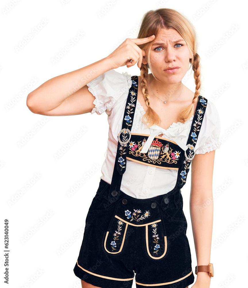 Young beautiful blonde woman wearing oktoberfest dress pointing unhappy to pimple on forehead, ugly infection of blackhead. acne and skin problem Young beautiful blonde woman wearing oktoberfest dress pointing unhappy to pimple on forehead, ugly infection of blackhead. acne and skin problem