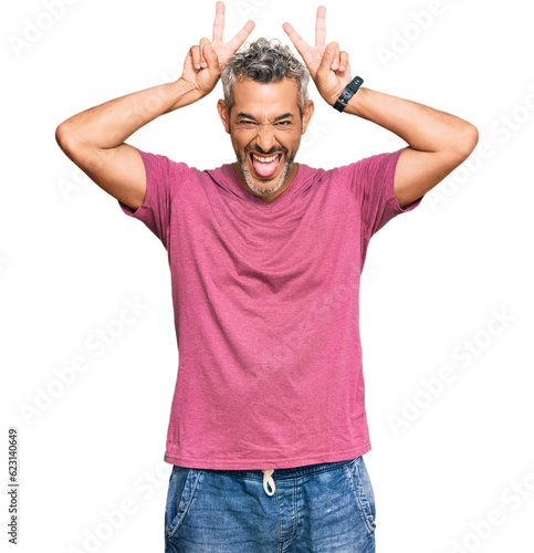 Middle age grey-haired man wearing casual clothes posing funny and crazy with fingers on head as bunny ears, smiling cheerful