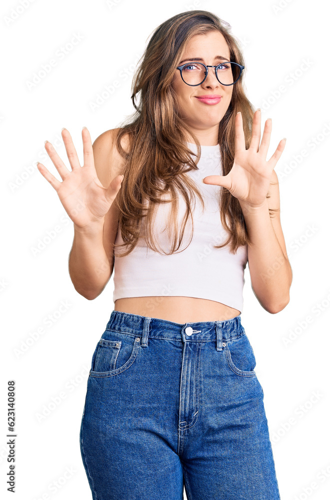 Beautiful caucasian young woman wearing casual clothes and glasses afraid and terrified with fear expression stop gesture with hands, shouting in shock. panic concept. Beautiful caucasian young woman wearing casual clothes and glasses afraid and terrified with fear expression stop gesture with hands, shouting in shock. panic concept.