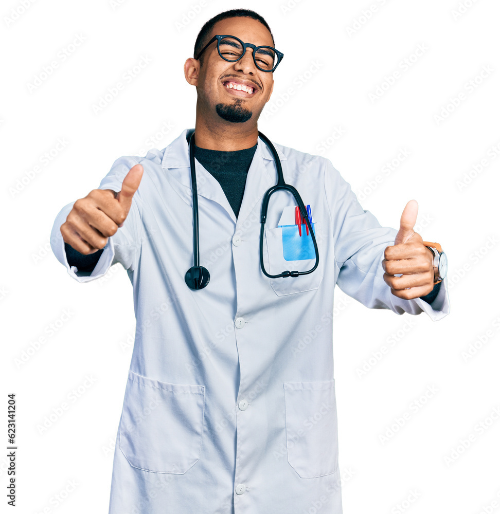 Young african american man wearing doctor uniform and stethoscope approving doing positive gesture with hand, thumbs up smiling and happy for success. winner gesture. Young african american man wearing doctor uniform and stethoscope approving doing positive gesture with hand, thumbs up smiling and happy for success. winner gesture.