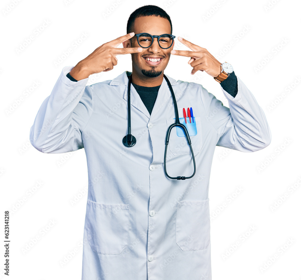 Young african american man wearing doctor uniform and stethoscope doing peace symbol with fingers over face, smiling cheerful showing victory