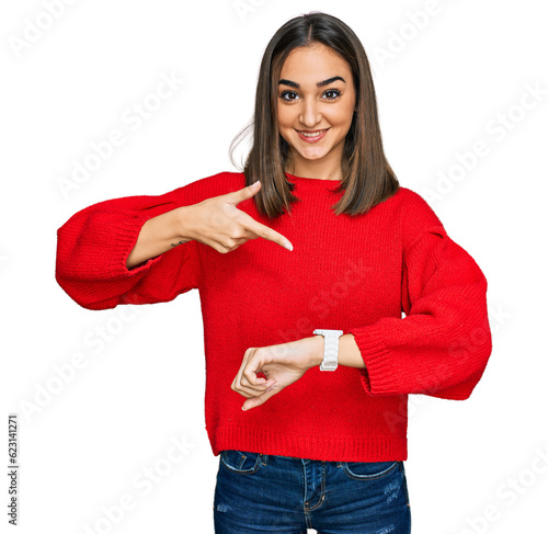 Принти на полотні Beautiful brunette woman wearing casual winter sweater in hurry pointing to watc
