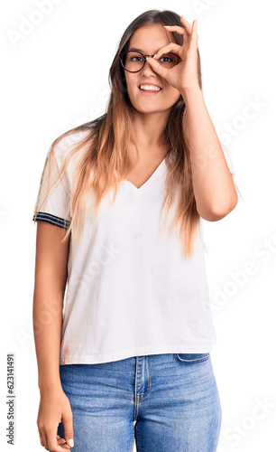 Beautiful caucasian woman wearing casual clothes and glasses doing ok sign with fingers, smiling friendly gesturing excellent symbol