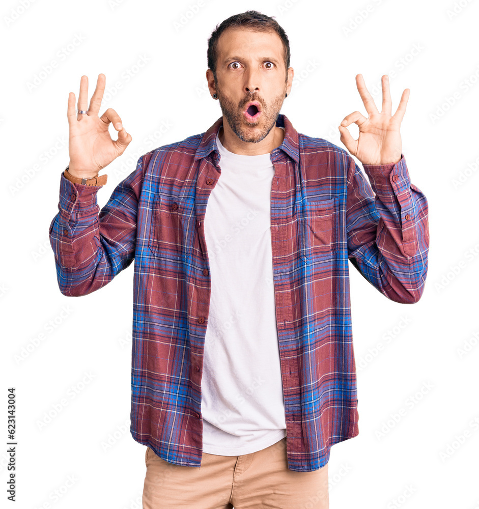 Young handsome man wearing casual clothes looking surprised and shocked doing ok approval symbol with fingers. crazy expression Young handsome man wearing casual clothes looking surprised and shocked doing ok approval symbol with fingers. crazy expression