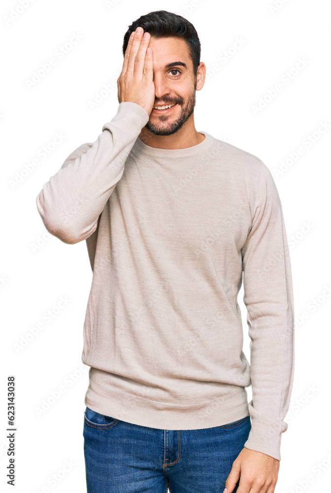 Young hispanic man wearing casual clothes covering one eye with hand, confident smile on face and surprise emotion. Young hispanic man wearing casual clothes covering one eye with hand, confident smile on face and surprise emotion.