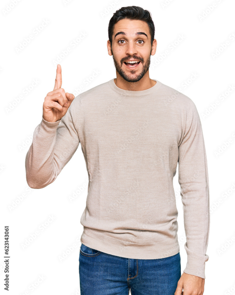 Young hispanic man wearing casual clothes pointing finger up with successful idea. exited and happy. number one. Young hispanic man wearing casual clothes pointing finger up with successful idea. exited and happy. number one.