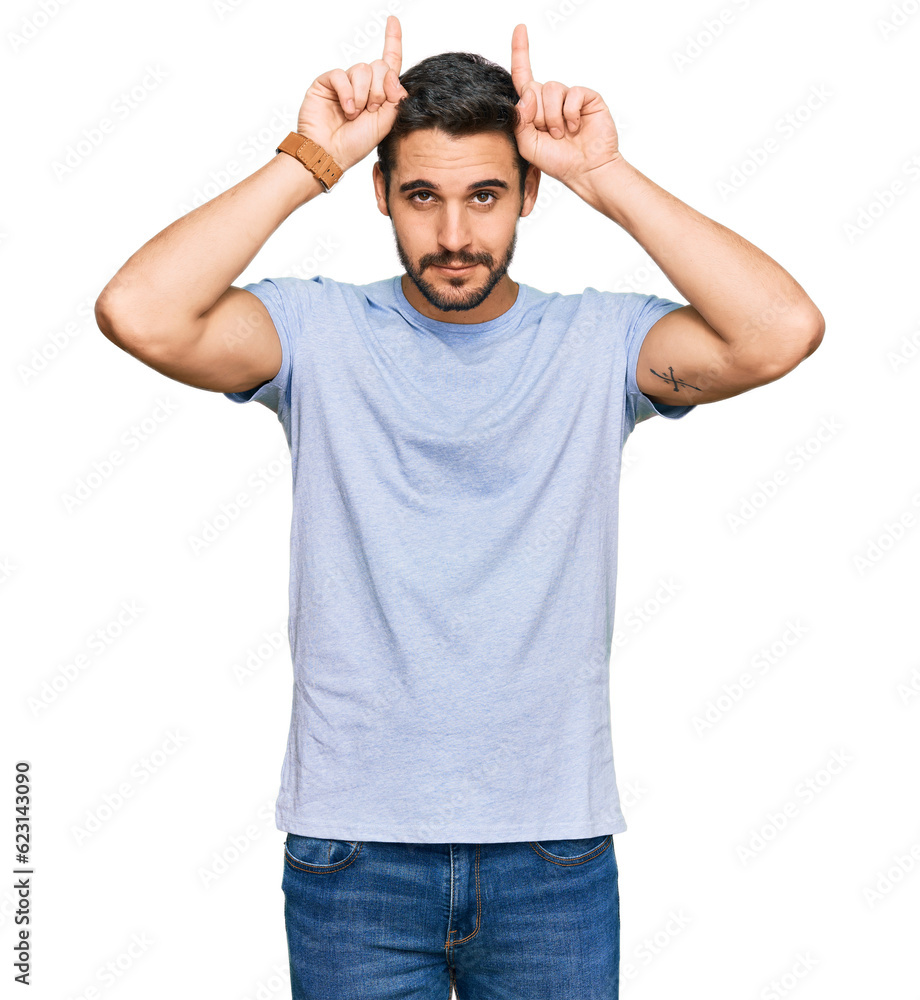 Fototapeta premium Young hispanic man wearing casual clothes doing funny gesture with finger over head as bull horns