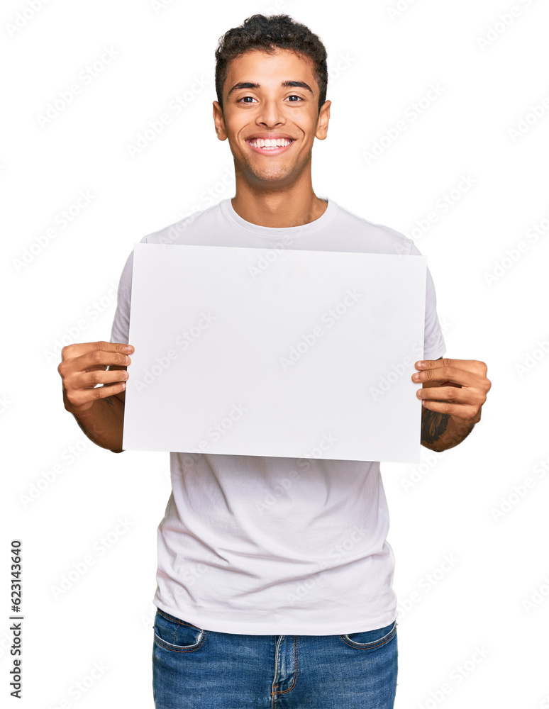 Young handsome african american man holding blank empty banner looking positive and happy standing and smiling with a confident smile showing teeth Young handsome african american man holding blank empty banner looking positive and happy standing and smiling with a confident smile showing teeth