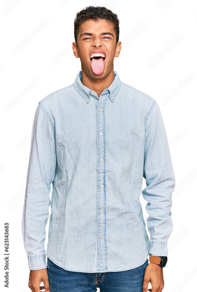 Young handsome african american man wearing casual clothes sticking tongue out happy with funny expression. emotion concept. Young handsome african american man wearing casual clothes sticking tongue out happy with funny expression. emotion concept.