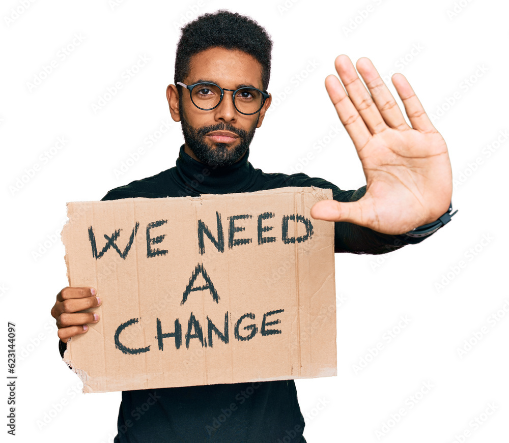 Young african american man holding we need a change banner with open hand doing stop sign with serious and confident expression, defense gesture Young african american man holding we need a change banner with open hand doing stop sign with serious and confident expression, defense gesture
