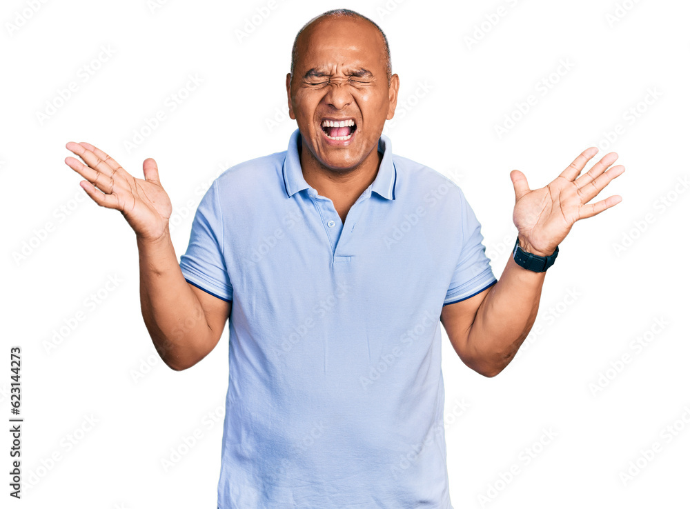 Naklejka premium Hispanic middle age man wearing casual t shirt celebrating mad and crazy for success with arms raised and closed eyes screaming excited. winner concept