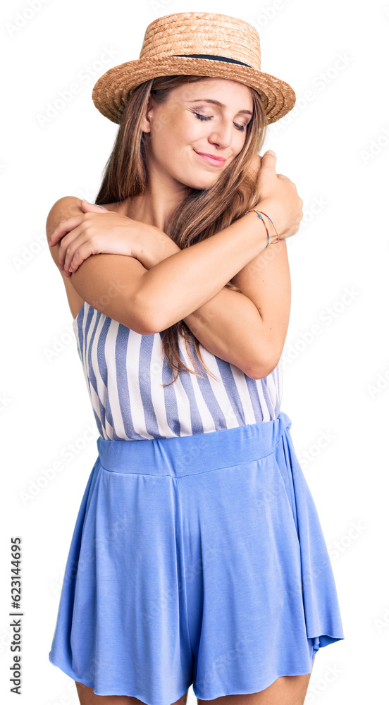 Young beautiful blonde woman wearing summer hat hugging oneself happy and positive, smiling confident. self love and self care Young beautiful blonde woman wearing summer hat hugging oneself happy and positive, smiling confident. self love and self care