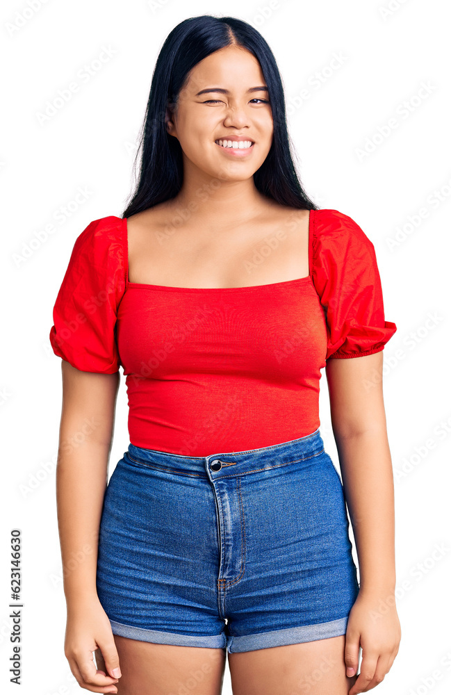 Young beautiful asian girl wearing casual clothes winking looking at the camera with sexy expression, cheerful and happy face. Young beautiful asian girl wearing casual clothes winking looking at the camera with sexy expression, cheerful and happy face.