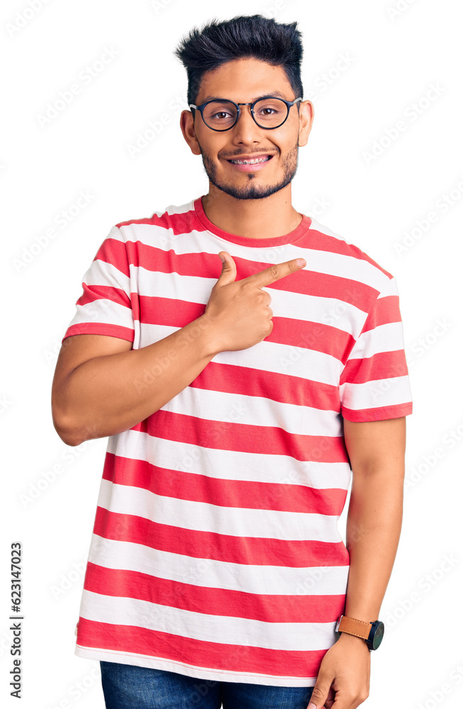 Handsome latin american young man wearing casual clothes and glasses cheerful with a smile on face pointing with hand and finger up to the side with happy and natural expression Handsome latin american young man wearing casual clothes and glasses cheerful with a smile on face pointing with hand and finger up to the side with happy and natural expression