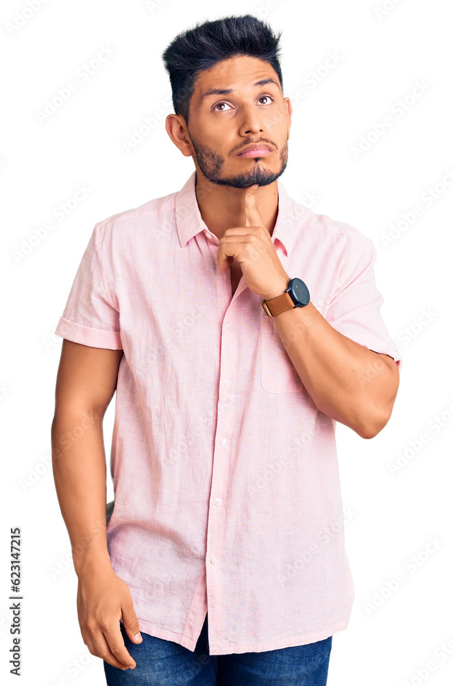 Handsome latin american young man wearing casual summer shirt thinking concentrated about doubt with finger on chin and looking up wondering Handsome latin american young man wearing casual summer shirt thinking concentrated about doubt with finger on chin and looking up wondering