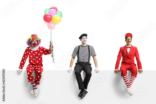 Clown, mime and an entertainer sitting on a white banner