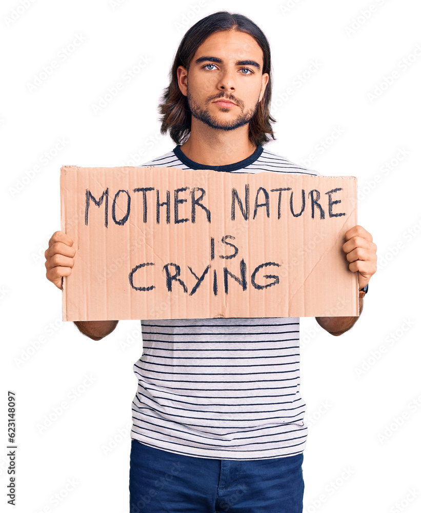 Young handsome man holding mother nature is crying protest cardboard banner thinking attitude and sober expression looking self confident Young handsome man holding mother nature is crying protest cardboard banner thinking attitude and sober expression looking self confident