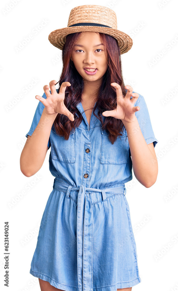 Young beautiful chinese girl wearing summer hat smiling funny doing claw gesture as cat, aggressive and sexy expression Young beautiful chinese girl wearing summer hat smiling funny doing claw gesture as cat, aggressive and sexy expression