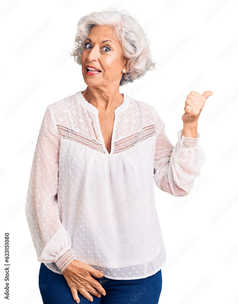 Senior grey-haired woman wearing casual clothes smiling with happy face looking and pointing to the side with thumb up. Senior grey-haired woman wearing casual clothes smiling with happy face looking and pointing to the side with thumb up.