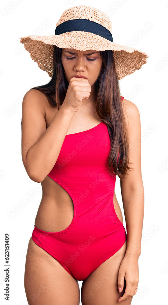 Young beautiful latin girl wearing swimwear and summer hat feeling unwell and coughing as symptom for cold or bronchitis. health care concept. Young beautiful latin girl wearing swimwear and summer hat feeling unwell and coughing as symptom for cold or bronchitis. health care concept.