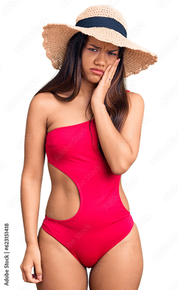 Young beautiful latin girl wearing swimwear and summer hat thinking looking tired and bored with depression problems with crossed arms. Young beautiful latin girl wearing swimwear and summer hat thinking looking tired and bored with depression problems with crossed arms.