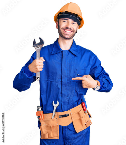 Tableau sur toile Young hispanic man wearing electrician uniform holding wrench pointing finger to