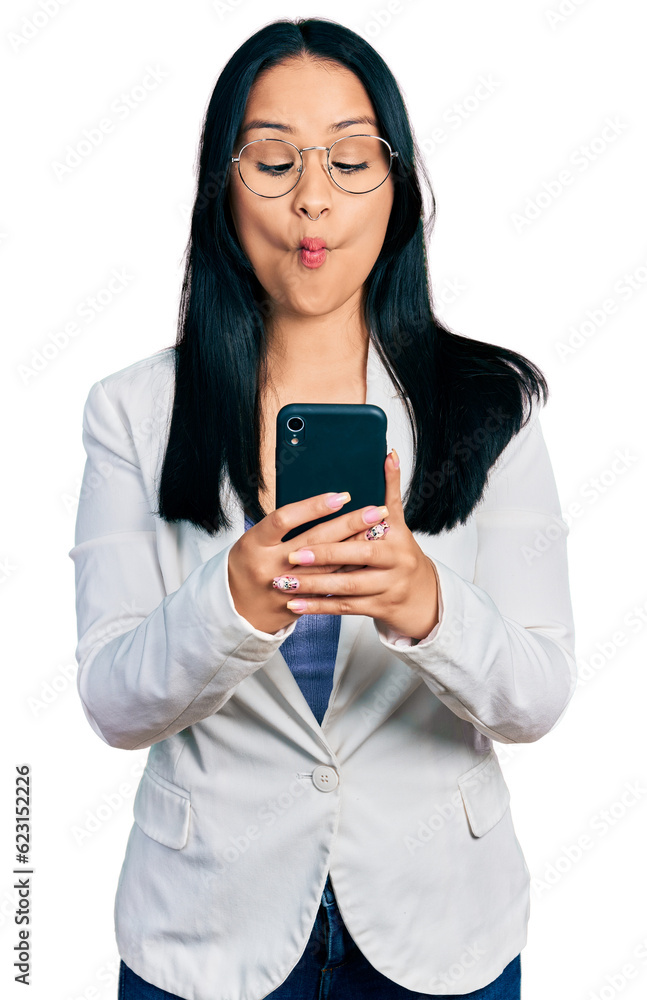 Beautiful hispanic woman with nose piercing using smartphone typing message making fish face with mouth and squinting eyes, crazy and comical. Beautiful hispanic woman with nose piercing using smartphone typing message making fish face with mouth and squinting eyes, crazy and comical.