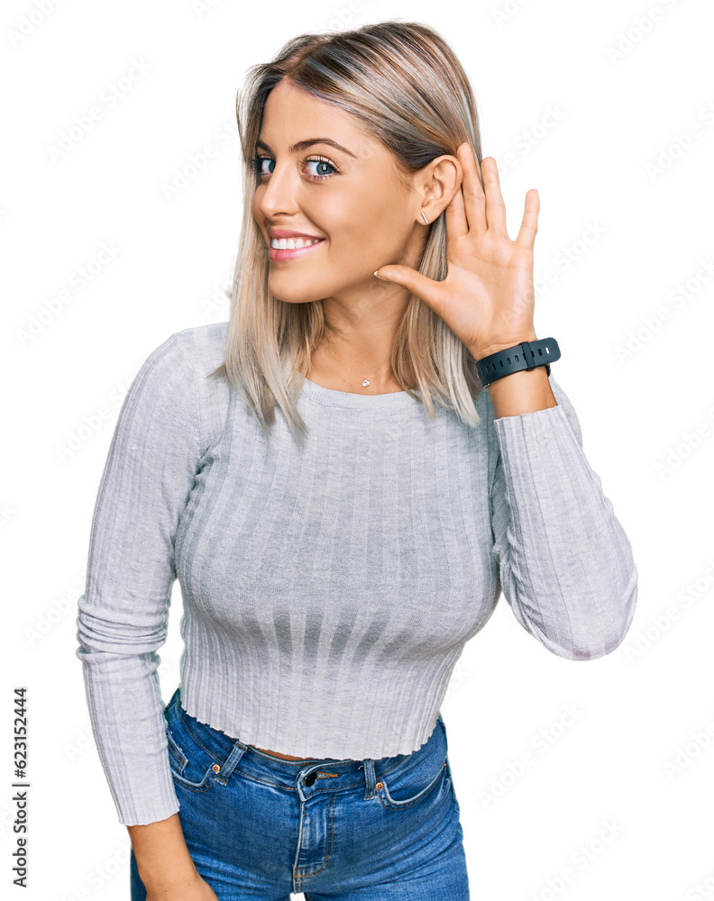 Beautiful blonde woman wearing casual clothes smiling with hand over ear listening an hearing to rumor or gossip. deafness concept. Beautiful blonde woman wearing casual clothes smiling with hand over ear listening an hearing to rumor or gossip. deafness concept.
