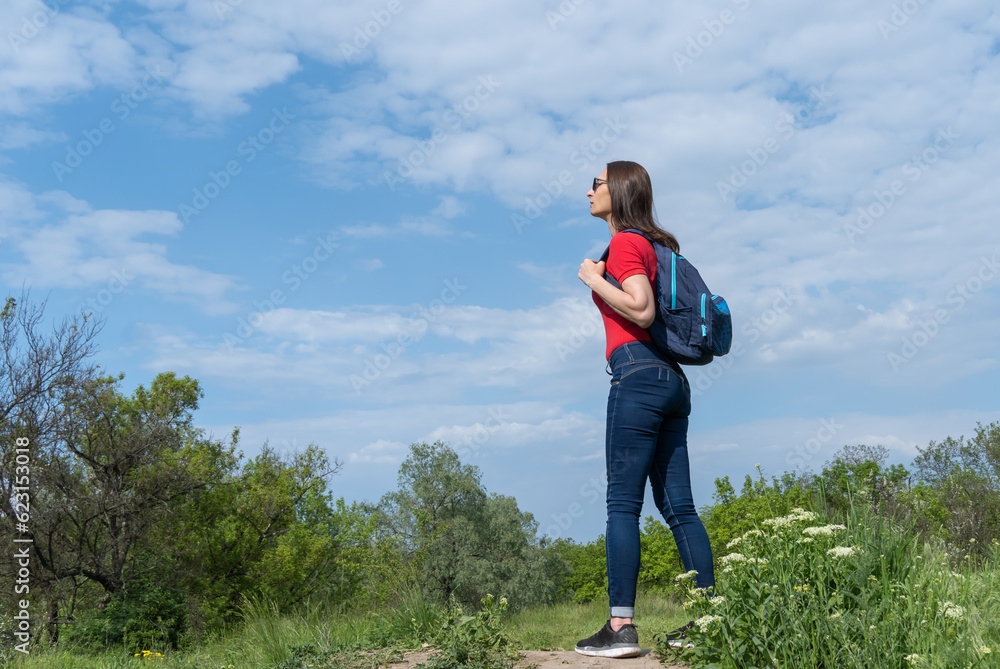 Tourist woman with backpack stand on edge and look on deciduous forest. Active adult leisure of hiking in green valley. Person enjoy wanderlust and view of the spring grassy hill. Female hiker explore Tourist woman with backpack stand on edge and look on deciduous forest. Active adult leisure of hiking in green valley. Person enjoy wanderlust and view of the spring grassy hill. Female hiker explore