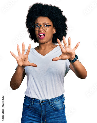 Young african american woman wearing casual white t shirt afraid and terrified with fear expression stop gesture with hands, shouting in shock. panic concept.