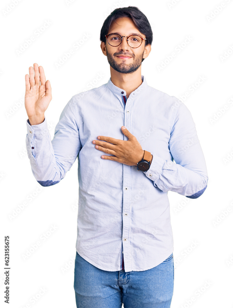 Handsome hispanic man wearing business shirt and glasses swearing with hand on chest and open palm, making a loyalty promise oath